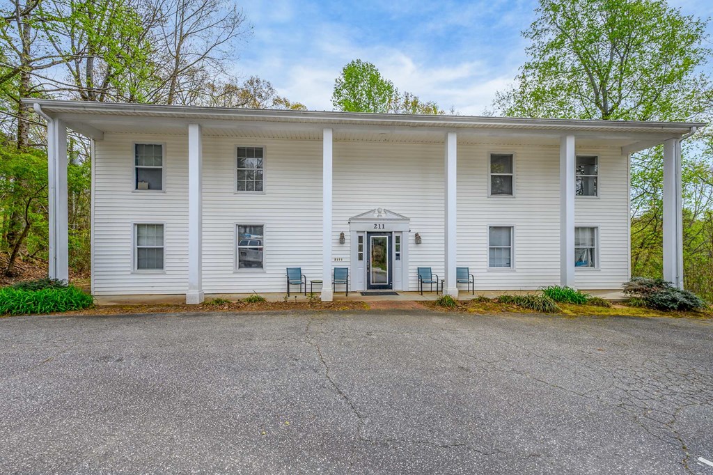 the front of a white house with columns and a black door