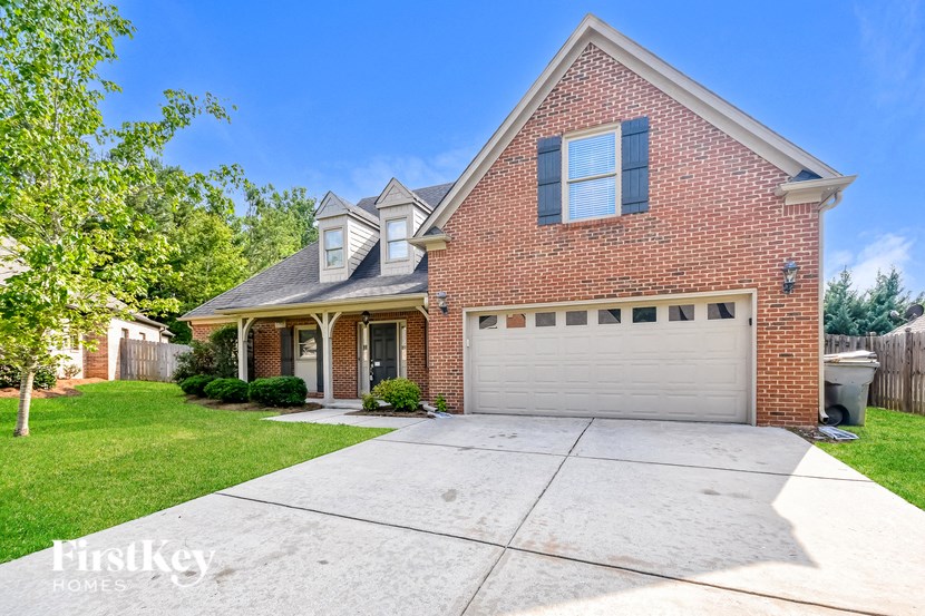 A brick house with a garage door and a tree in front.