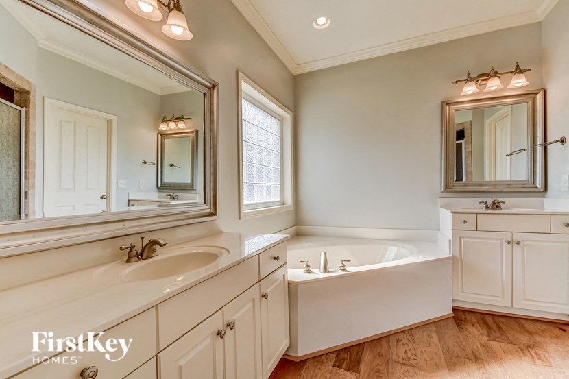 A bathroom with a tub, sink, and mirror.