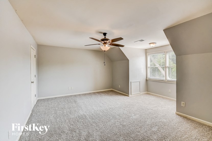 A spacious room with a ceiling fan and a window with blinds.