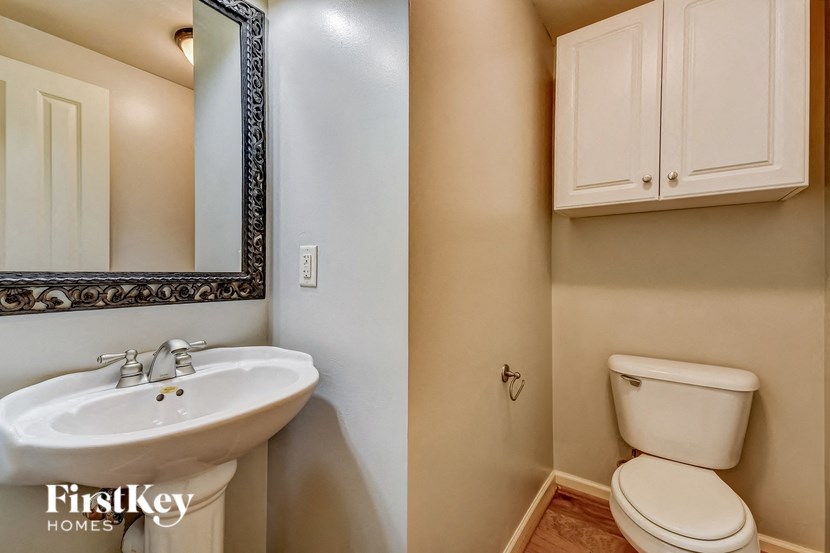 A bathroom with a toilet, sink and mirror.