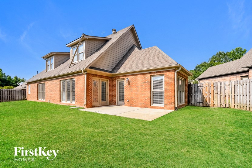 A brick house with a white fence in front.