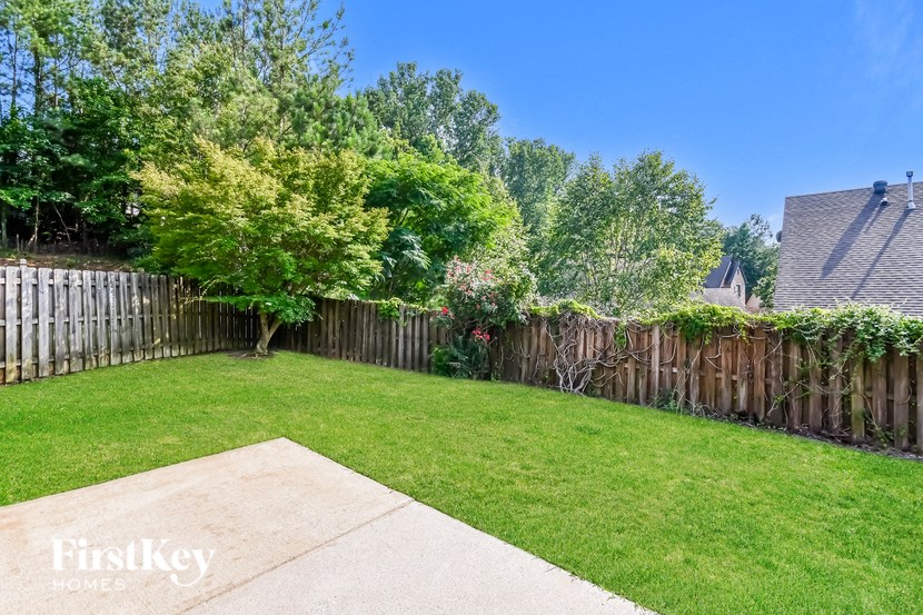 A backyard with a wooden fence and a concrete slab.