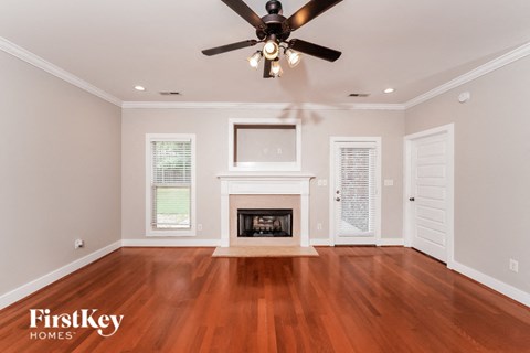 A spacious room with a fireplace and a ceiling fan.