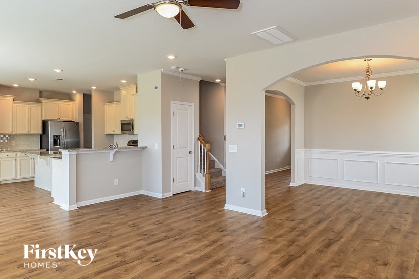 A spacious kitchen and living room with wooden floors and a ceiling fan.