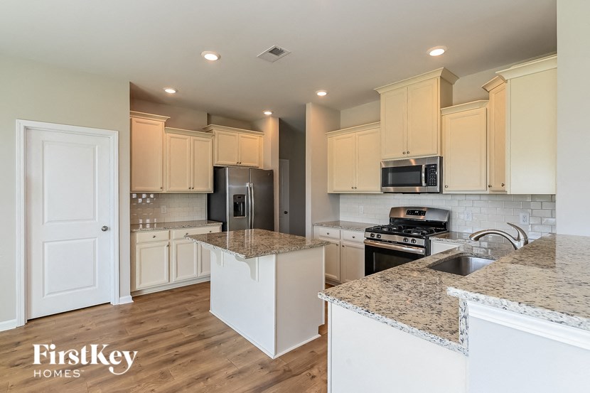 A kitchen with a granite countertop and wooden floors.