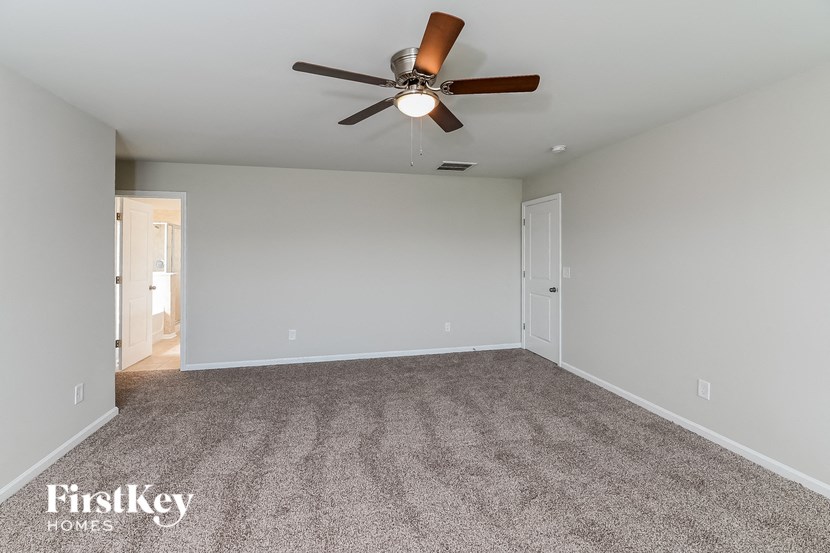 A room with a ceiling fan and carpeted floor.