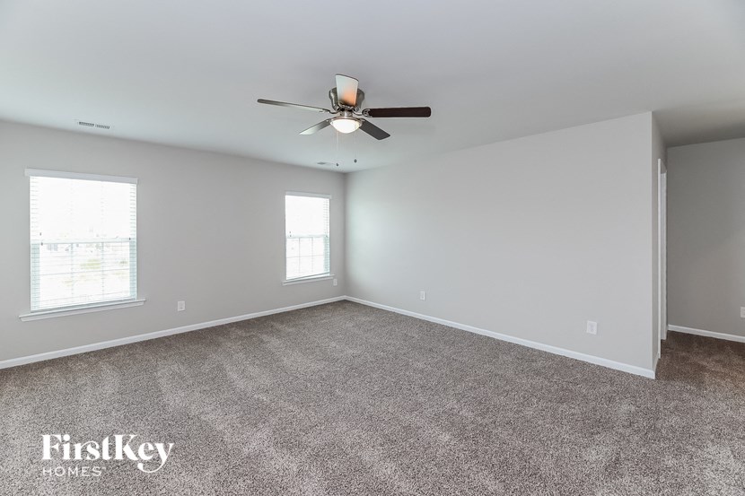 A spacious room with a ceiling fan and carpeted floor.