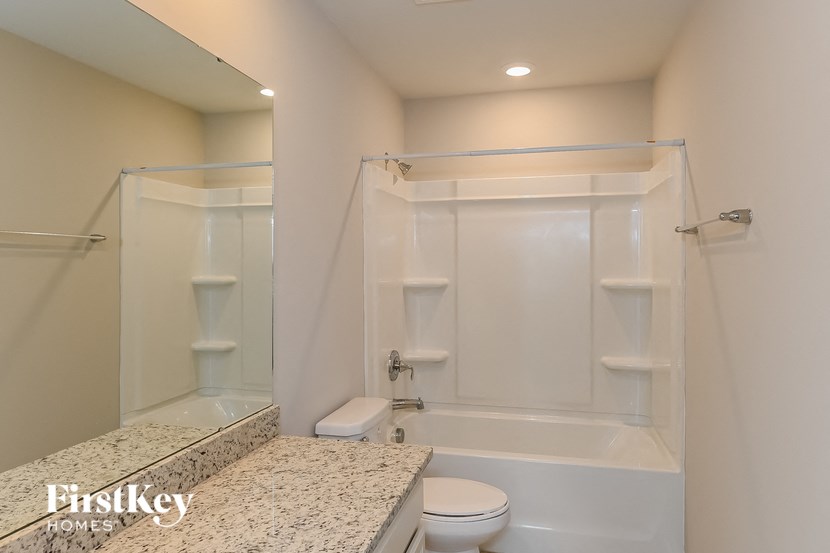 A white bathroom with a tub, toilet and sink.