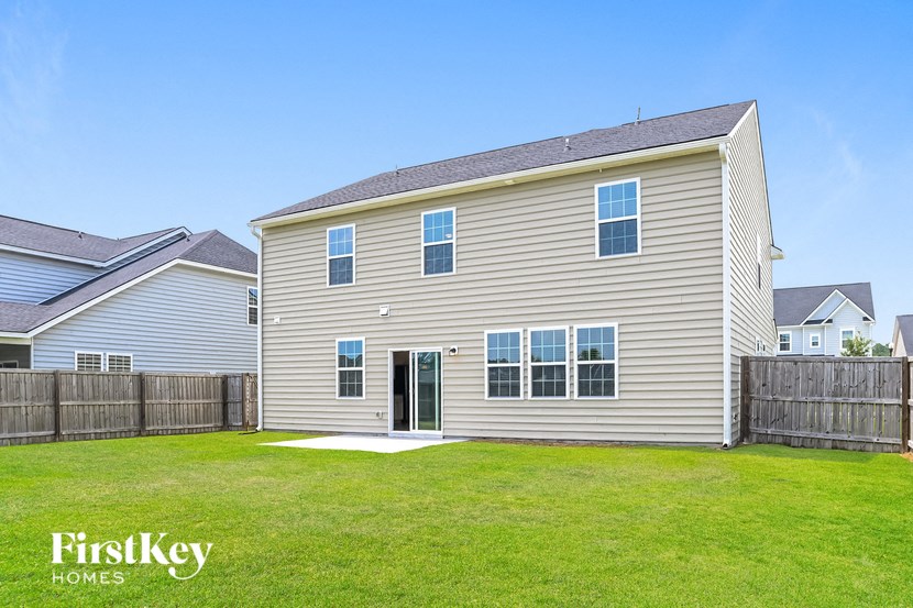 A house with a grey siding and a brown fence is for sale by FirstKey Homes.