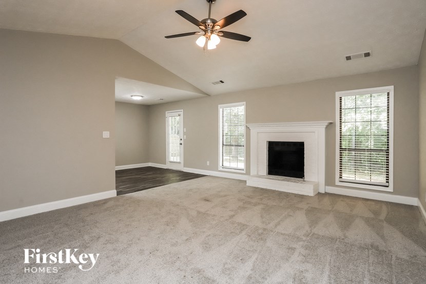 an empty living room with a fireplace and a ceiling fan