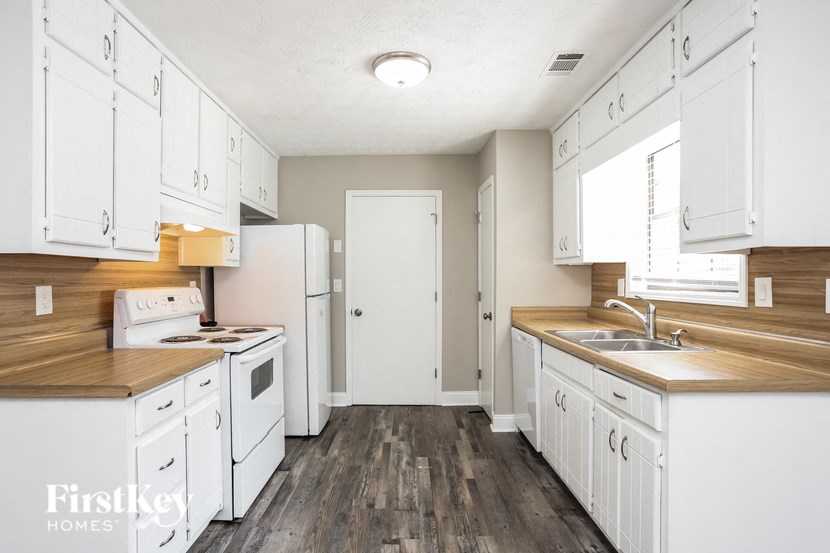 a white kitchen with wooden floors and white appliances