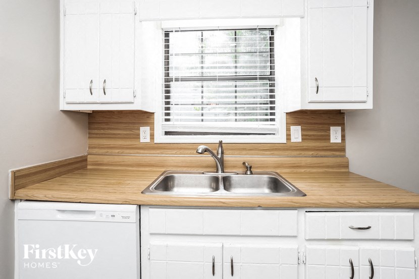 a kitchen with white cabinets and a sink and a window