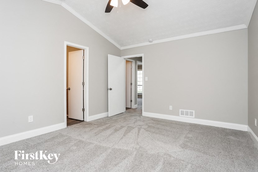 an empty living room with a ceiling fan and a door to a hallway