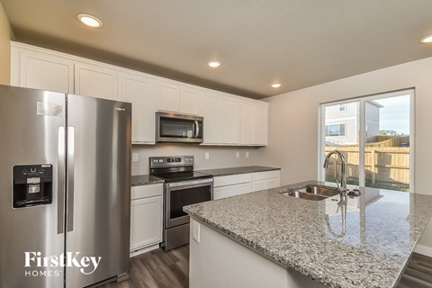 A kitchen with a stainless steel refrigerator and a granite countertop.