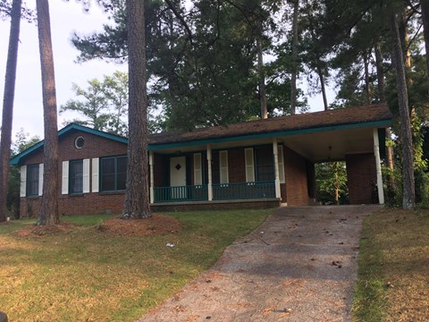 the front of a house with a porch and trees