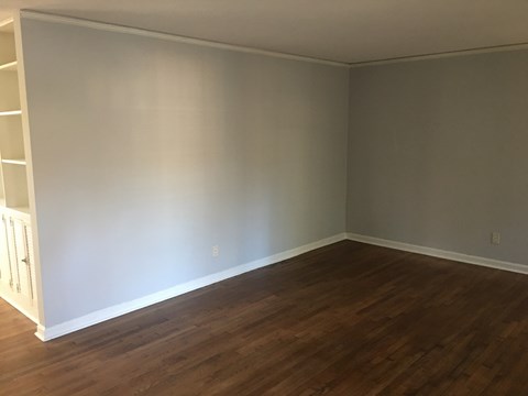 an empty living room with wooden floors and grey walls