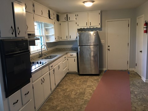 an empty kitchen with white cabinets and stainless steel appliances