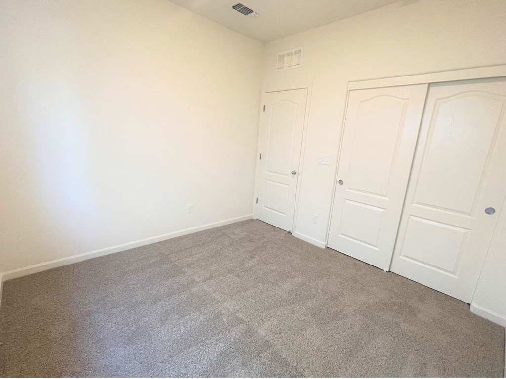 an empty bedroom with three closets and carpeting