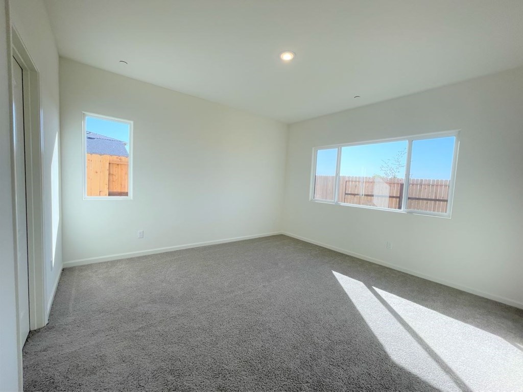 a living room with carpet and two windows