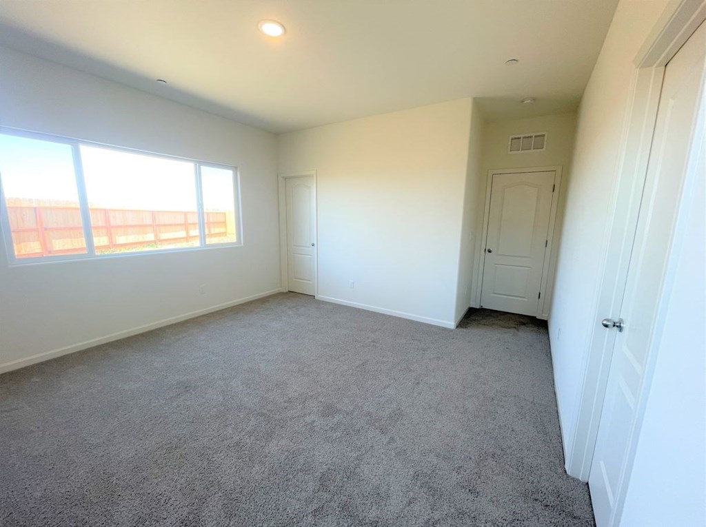 a bedroom with carpet and white walls and a door