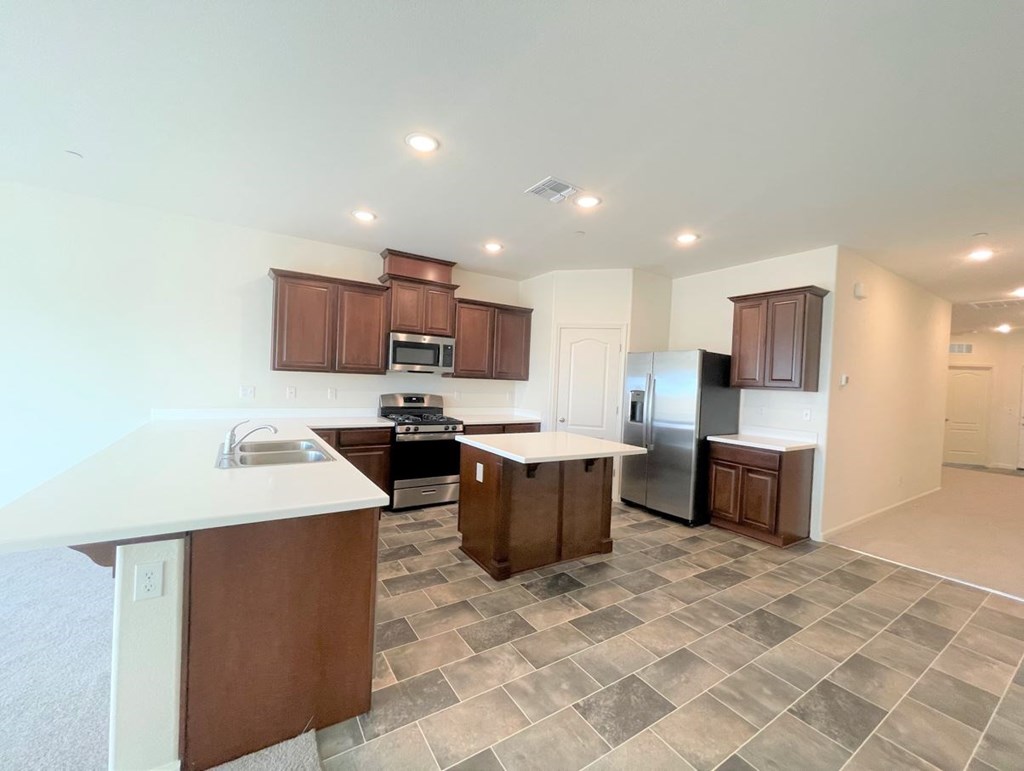 a kitchen with an island and a stainless steel refrigerator