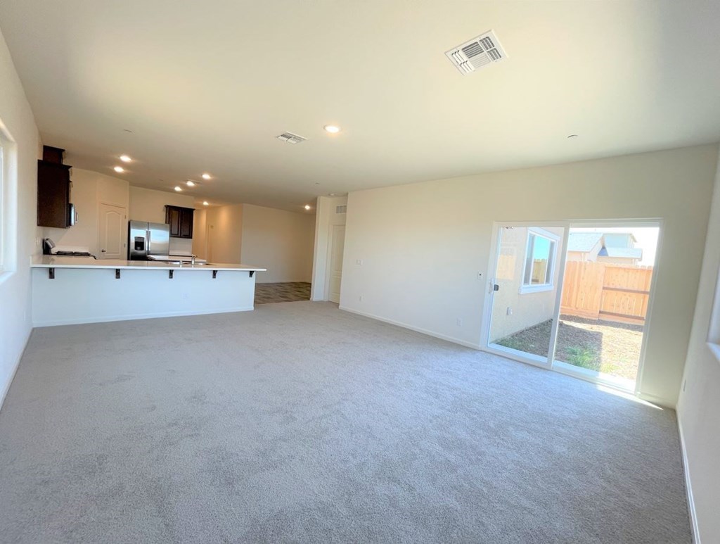 a empty living room with a kitchen and a glass door