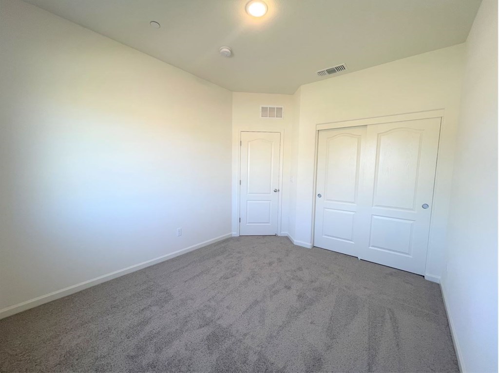 a bedroom with white walls and carpet and two doors