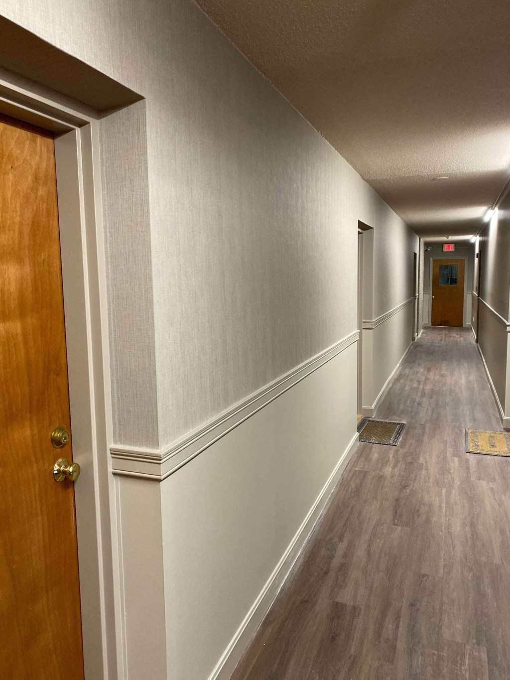 a hallway with wood floors and gray walls and a wooden door
