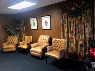 a waiting room with four chairs and a plant