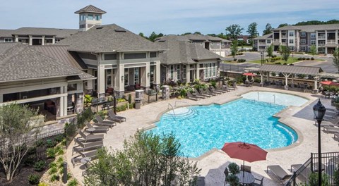 a large swimming pool with lounge chairs in front of a building