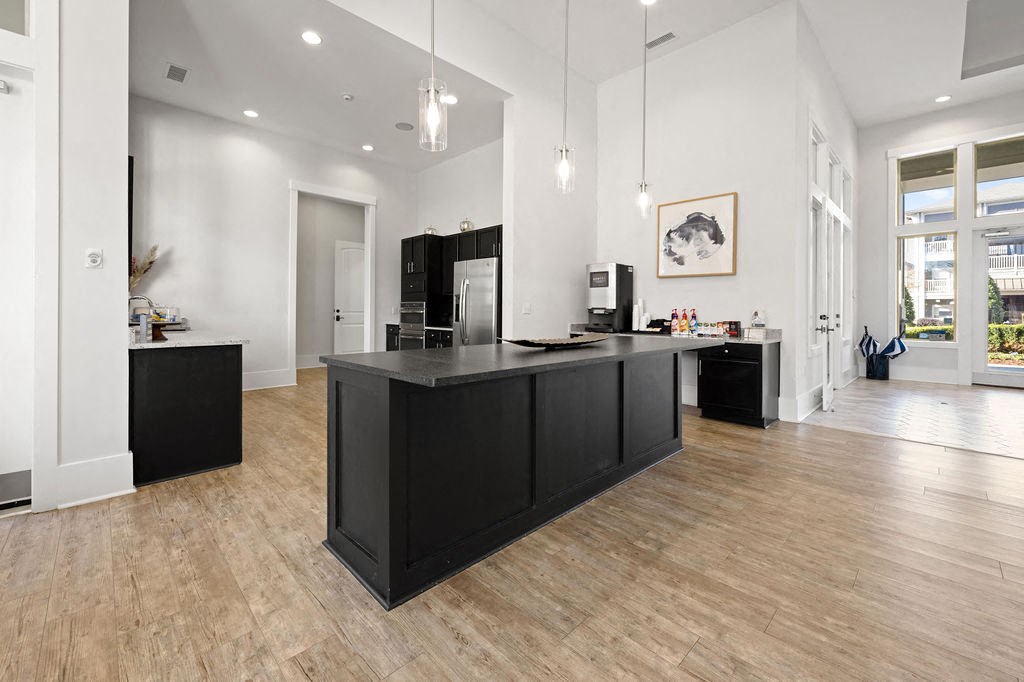 A modern kitchen with a black island and wooden floors.