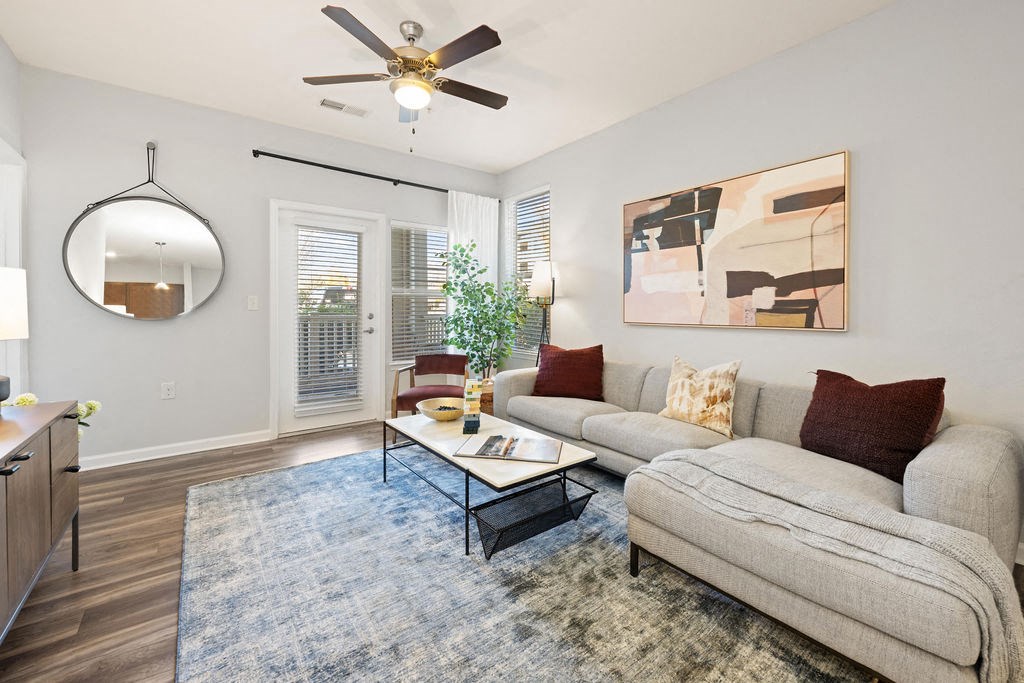 A living room with a grey couch, a coffee table, and a ceiling fan.