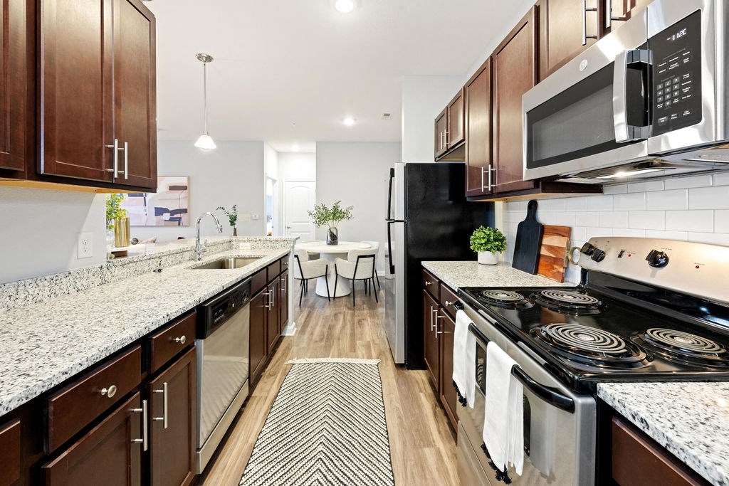 A kitchen with dark brown cabinets and black appliances.