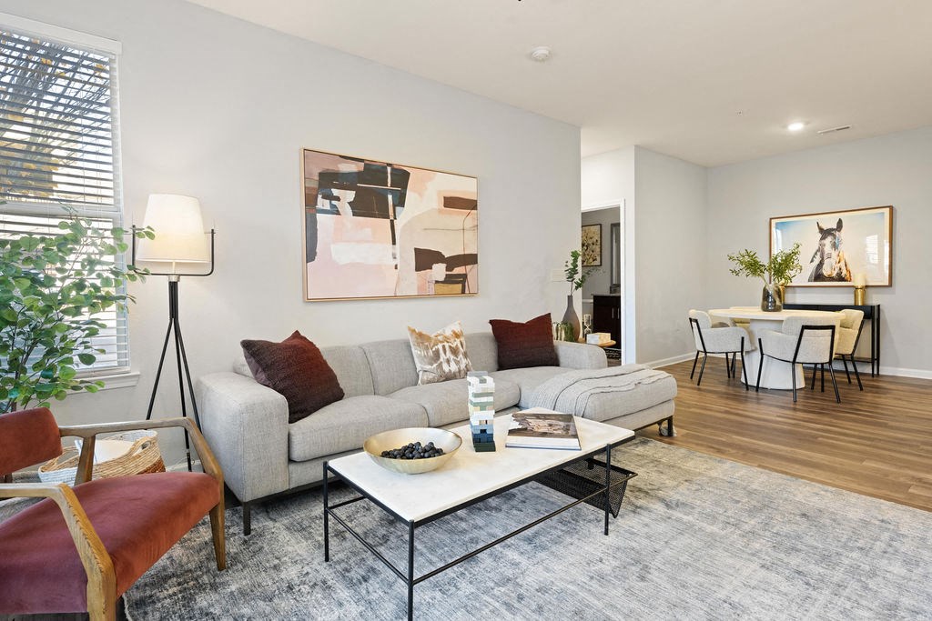 A living room with a grey couch, a coffee table, and a painting on the wall.