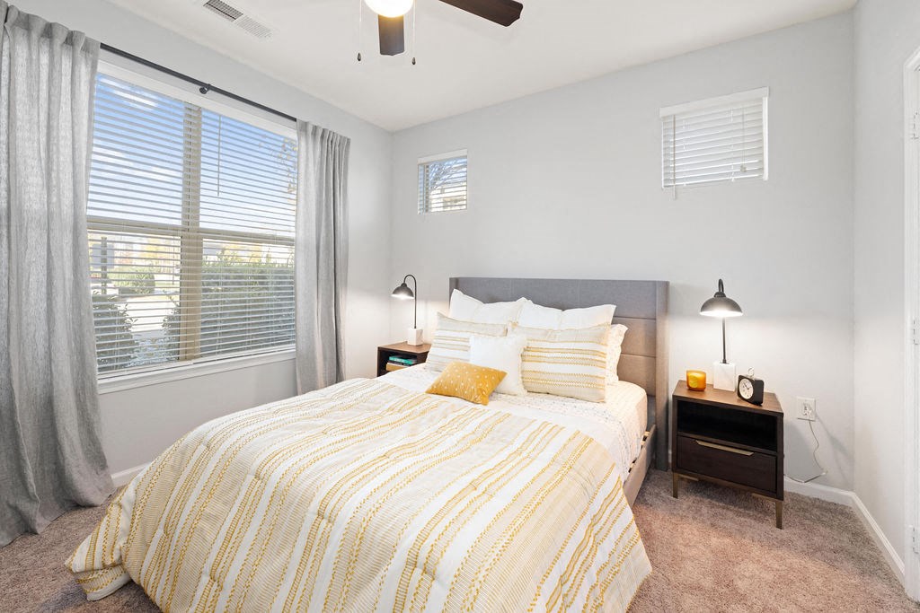 A bedroom with a bed, nightstand, and window.