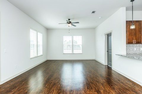 A spacious room with a ceiling fan and wooden flooring.