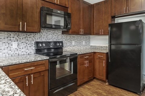 A kitchen with black appliances and brown cabinets.