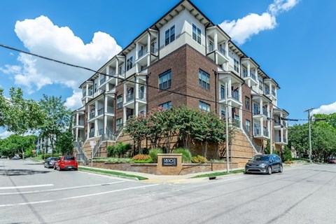 A street view of a multi-story building with cars parked in front.