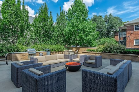 A patio with blue wicker furniture and a red bowl in the center.