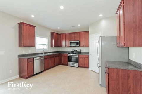 A kitchen with red cabinets and a grey counter top.