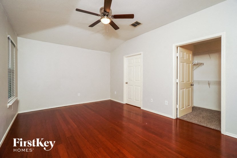 an empty living room with wood floors and a ceiling fan