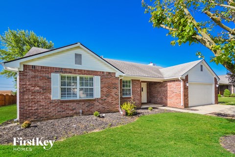 a small brick house with a lawn and a tree
