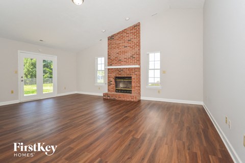 the living room with hardwood floors and a brick fireplace