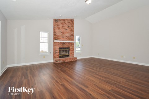 the living room with wood floors and a brick fireplace