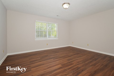 the spacious living room with hardwood flooring and a window