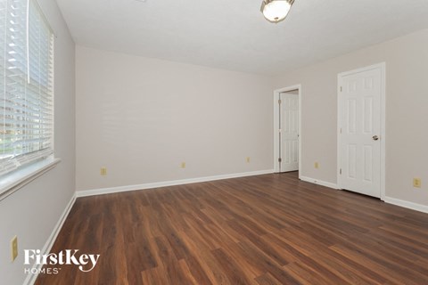 the spacious living room with wood flooring and white walls