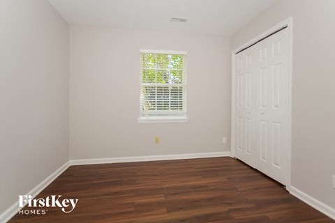 a bedroom with white walls and wood floors and a white door