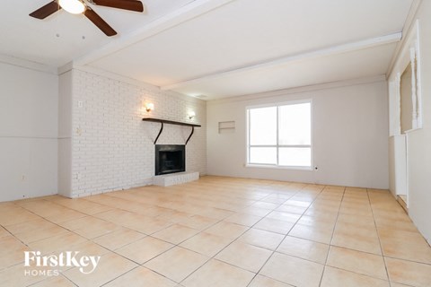 A spacious room with a fireplace and a ceiling fan.