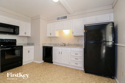 A kitchen with black appliances and white cabinets.